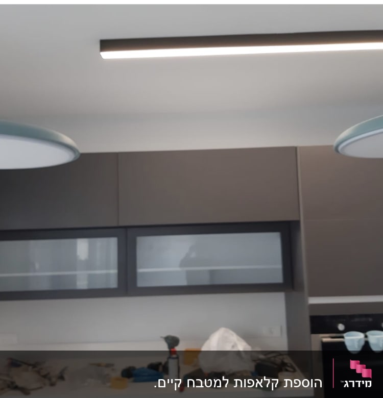 מטבח עם ארונות כהים, כלים על השיש